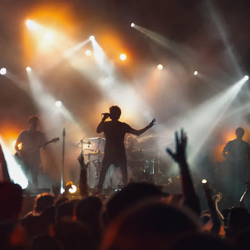 Show ao vivo visto da plateia, com mãos levantadas e feixes de luz